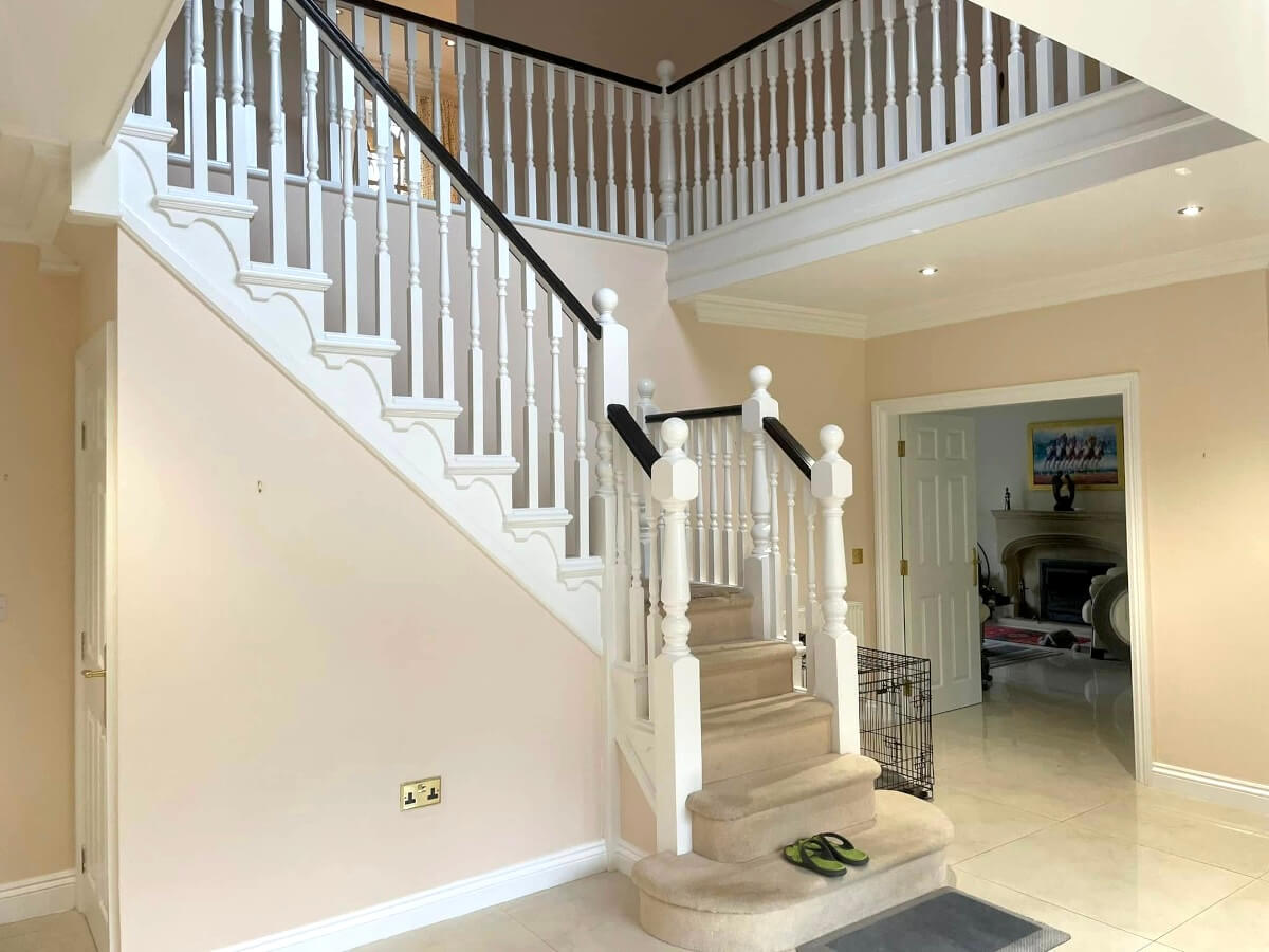 Entrance hall with cream painted walls and a white staircase with a curved landing