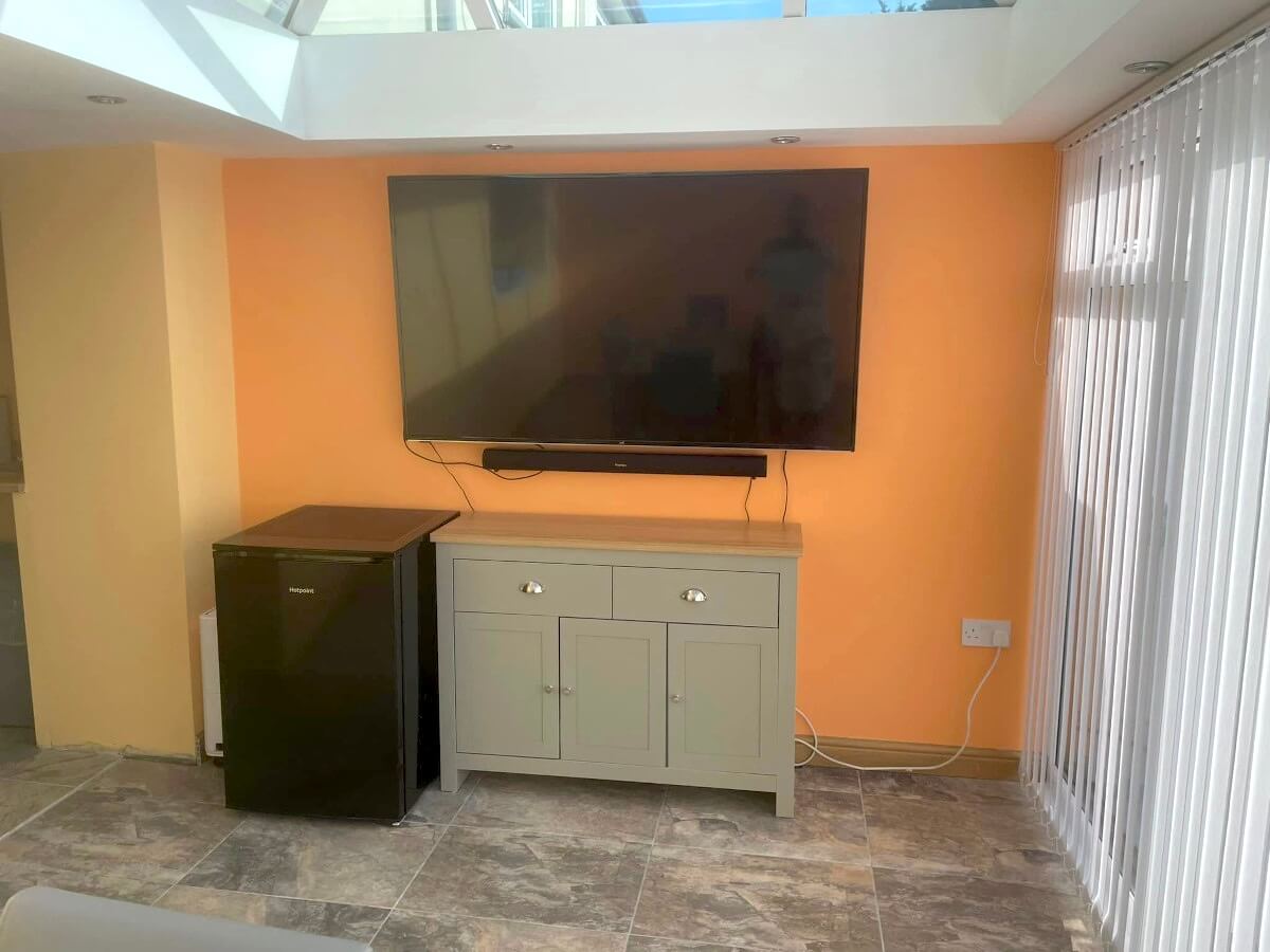 family-room-peach-painted-walls-tv-skylight-cardiff-primrose-decor Room with an orange painted wall and a large wall-mounted TV in Cardiff