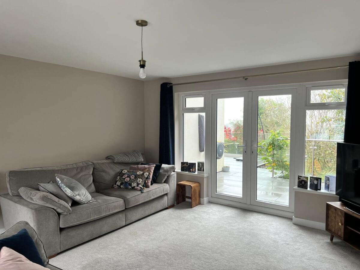 Living room with cream painted walls, grey sofa and French doors
